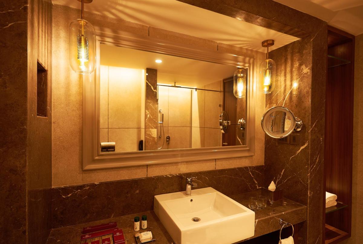 a bathroom with a sink and a mirror at The Residency Towers Puducherry in Puducherry