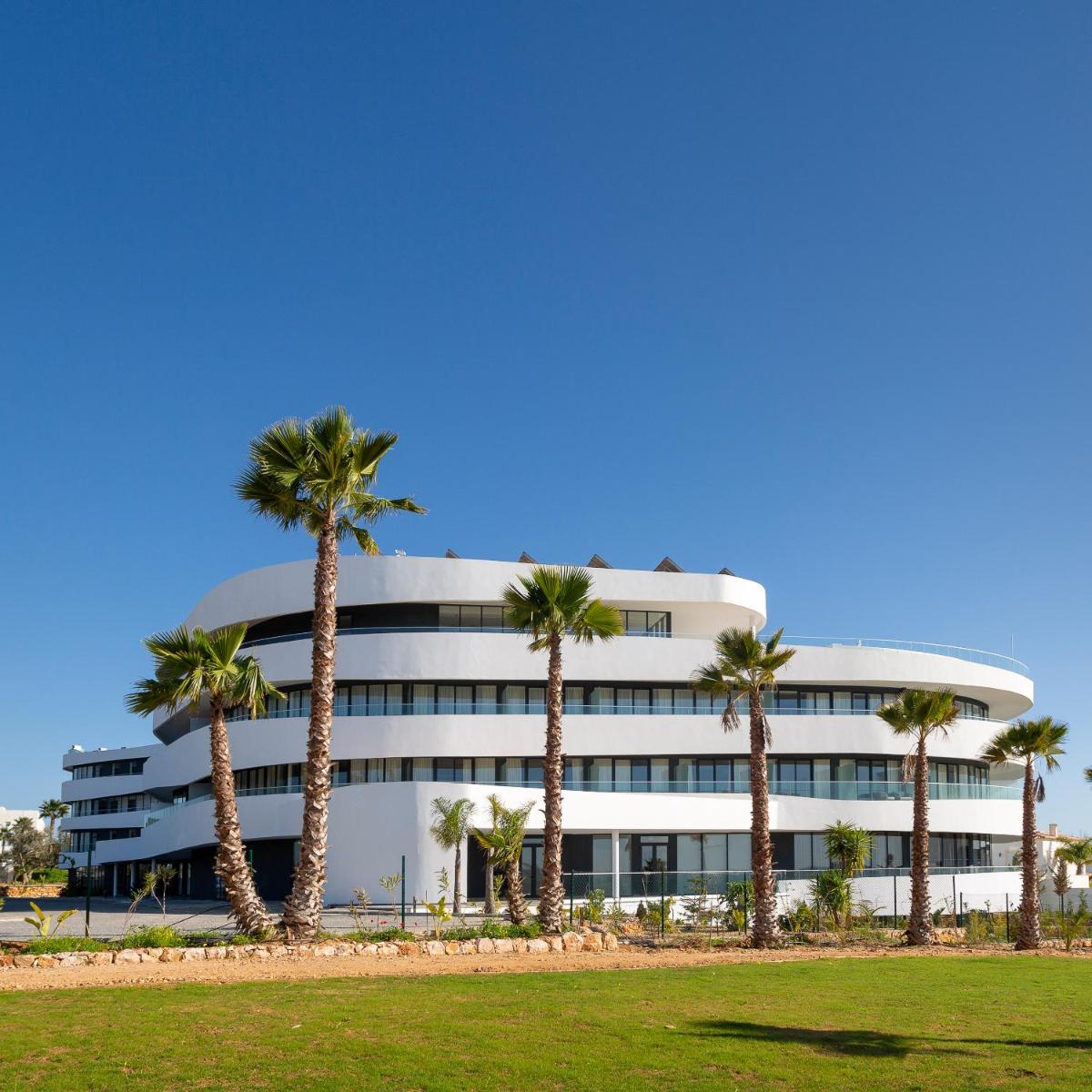um prédio com palmeiras na frente em Longevity Health & Wellness Hotel - Adults Only em Alvor