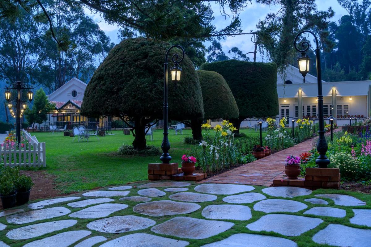 a stone walkway with lights and flowers in a yard at Savoy - IHCL SeleQtions in Ooty
