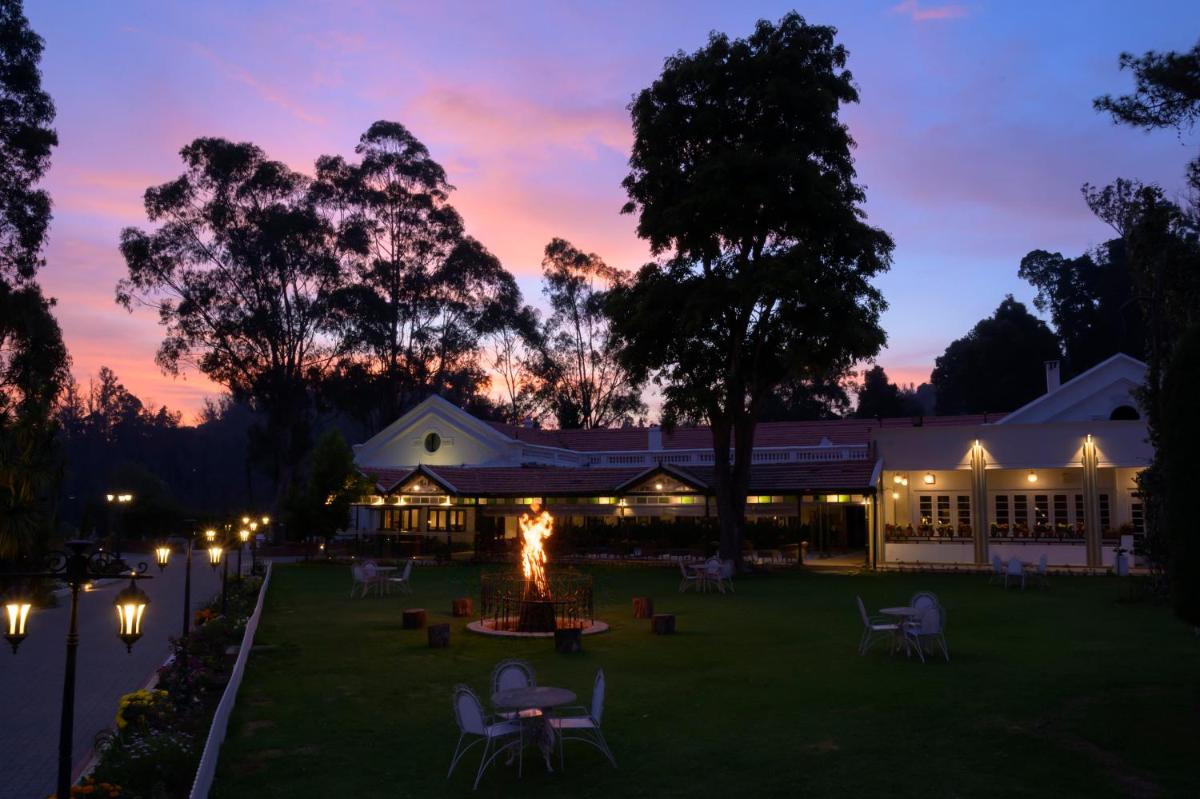 a building with a fire in the yard at dusk at Savoy - IHCL SeleQtions in Ooty