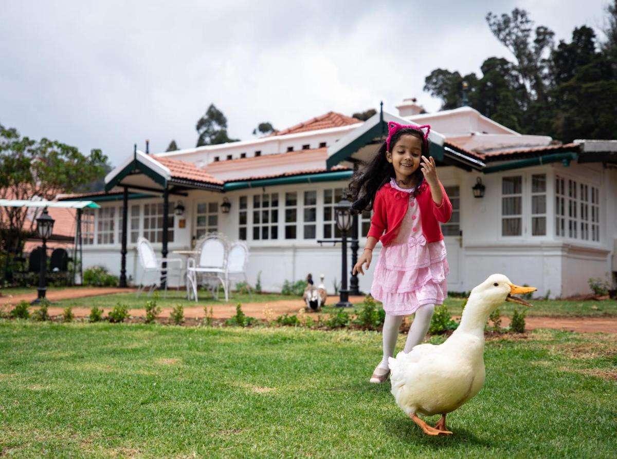 a little girl running after a duck in the grass at Savoy - IHCL SeleQtions in Ooty