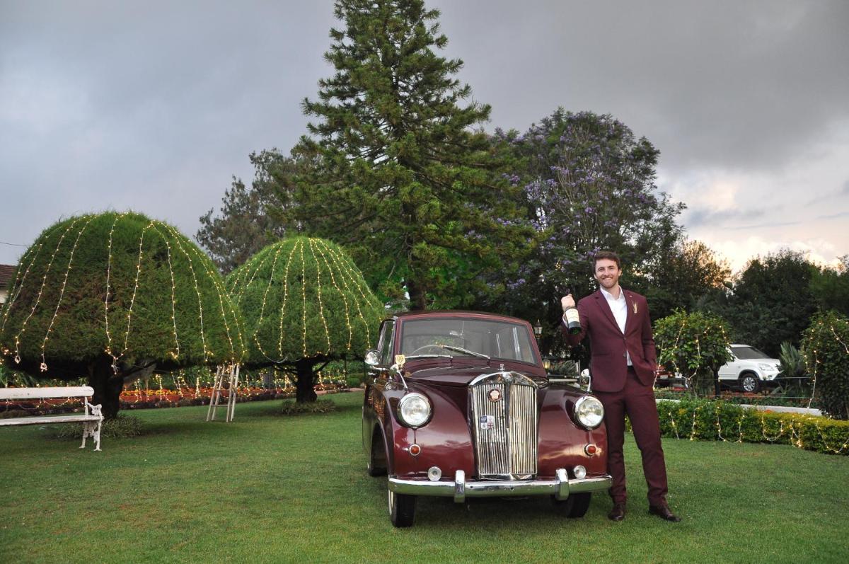 a man in a suit standing next to a car at Savoy - IHCL SeleQtions in Ooty