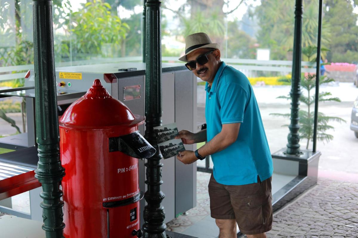 a man standing next to a red fire hydrant at Savoy - IHCL SeleQtions in Ooty
