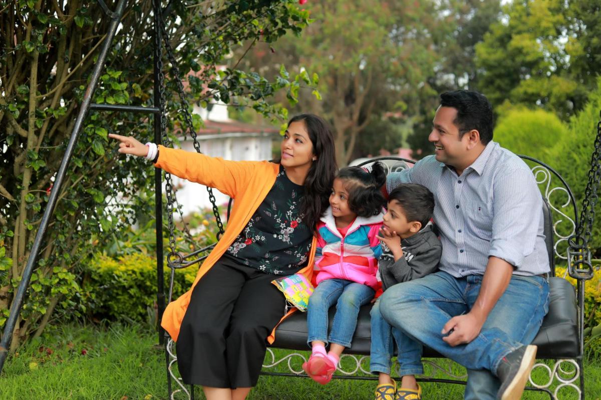 a family is sitting on a park bench at Savoy - IHCL SeleQtions in Ooty