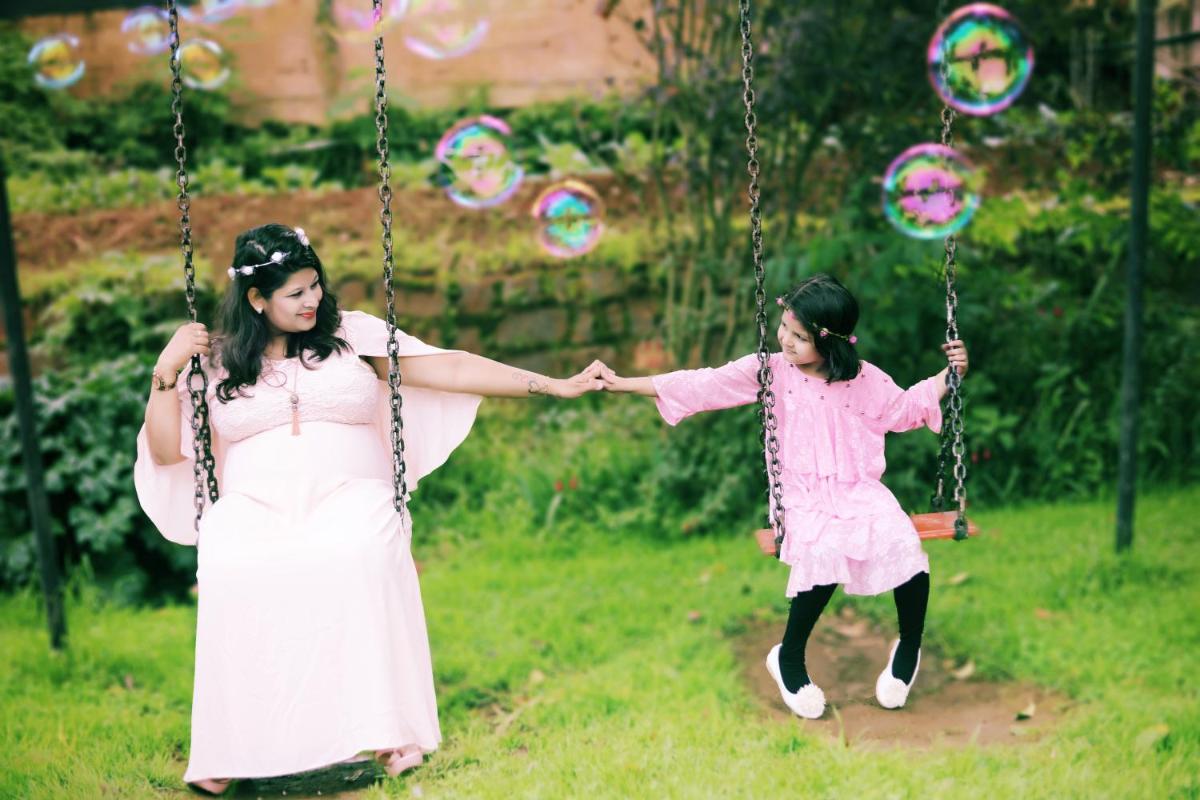 a woman and a little girl on a swing at Savoy - IHCL SeleQtions in Ooty