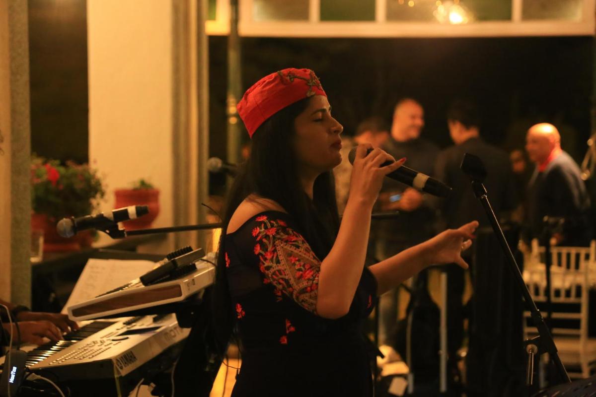 a woman in a red hat singing into a microphone at Savoy - IHCL SeleQtions in Ooty