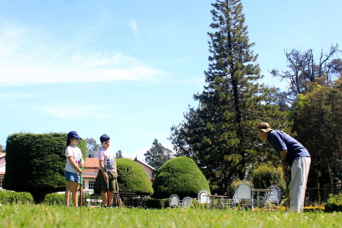 a group of people standing in the grass at Savoy - IHCL SeleQtions in Ooty