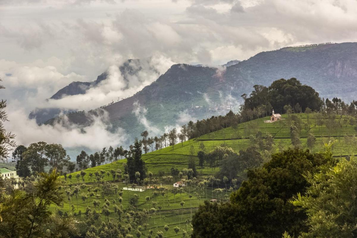 a green hillside with trees and mountains in the background at Savoy - IHCL SeleQtions in Ooty