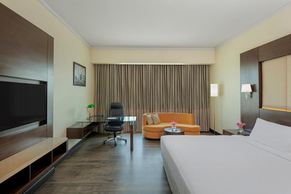 a hotel room with a bed and a couch and a table at Radisson Blu Plaza Hotel Mysore in Mysore