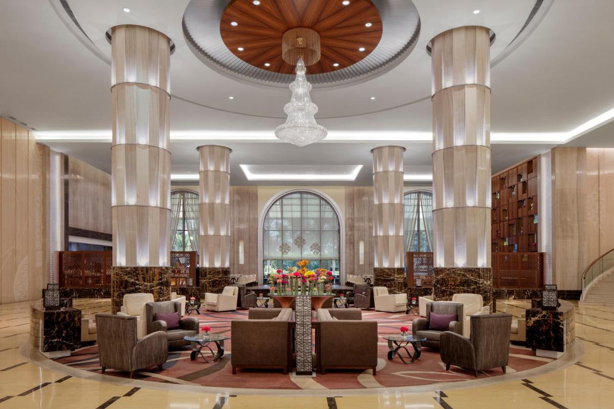 a lobby with couches and chairs and a chandelier at Radisson Blu Plaza Hotel Mysore in Mysore