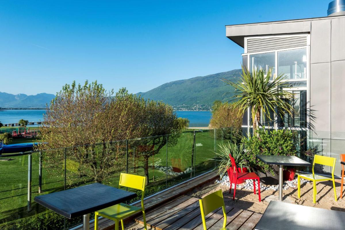 un balcon avec tables et chaises et vue sur l'eau dans l'établissement Best Western Aquakub, à Aix-les-Bains