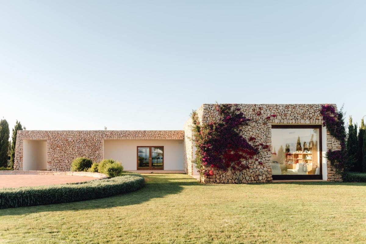 una casa de piedra con una gran ventana en un patio en Torralbenc, a Small Luxury Hotel of the World, en Cala'n Porter 117 fotos más