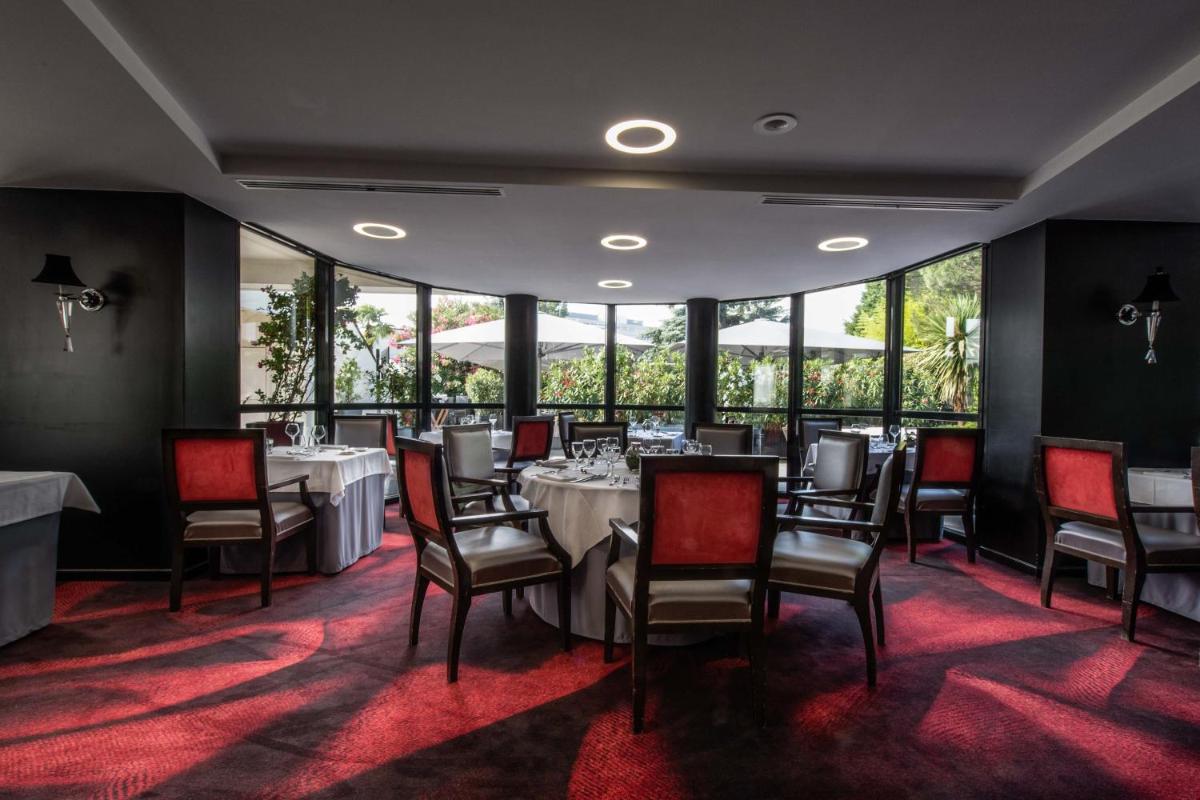 une salle à manger avec tables et chaises et de grandes fenêtres dans l'établissement Hotel Palladia, à Toulouse