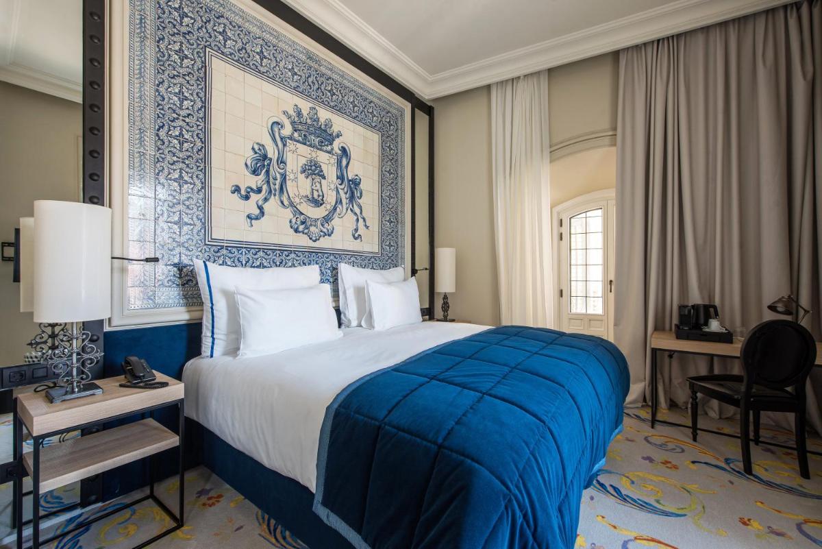 Un dormitorio con una cama azul y blanca y un escritorio. en Pestana Collection Plaza Mayor, en Madrid