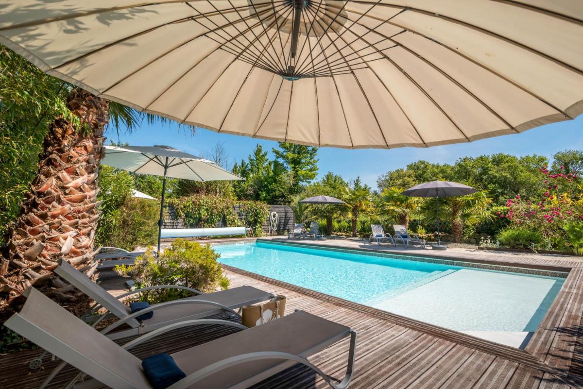 une piscine avec des chaises et un parasol dans l'établissement Carnac Lodge Hotel & Spa, à Plouharnel