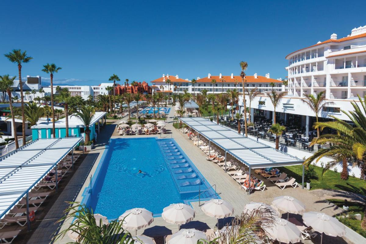 Una vista aérea de una piscina de un complejo turístico con sombrillas. en Hotel Riu Arecas - Adults Only, en Adeje