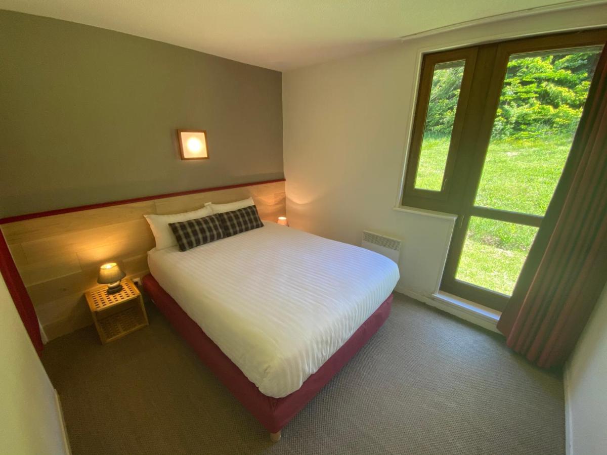 une chambre avec un lit et une grande fenêtre dans l'établissement Sancy Resort, à Chambon-sur-Lac
