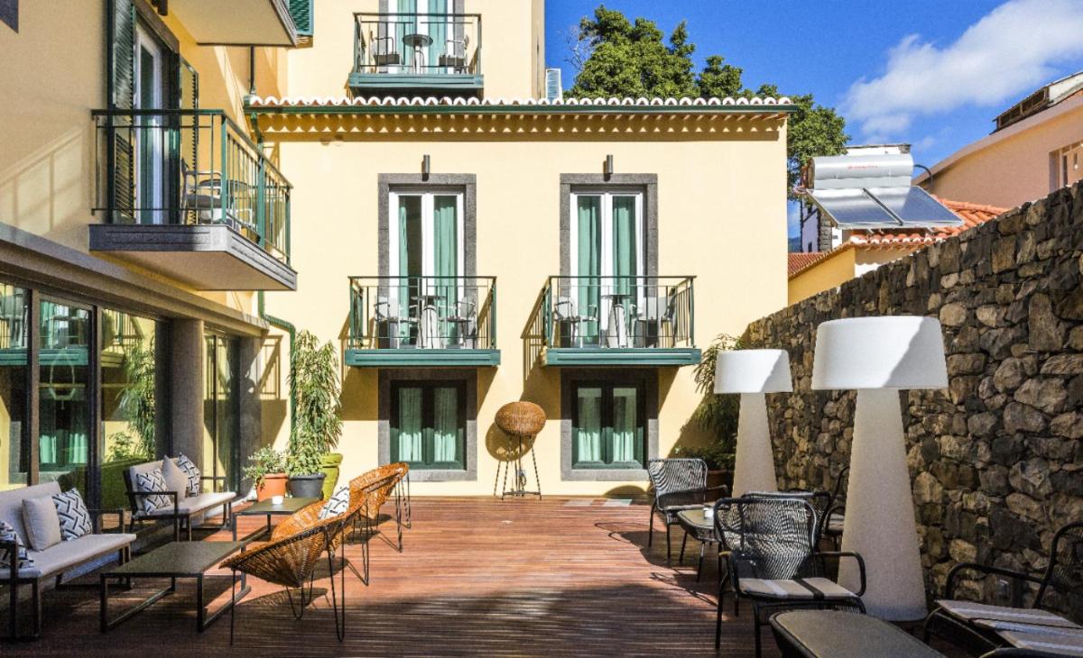 um pátio com cadeiras e mesas em frente a um prédio em Castanheiro Boutique Hotel no Funchal