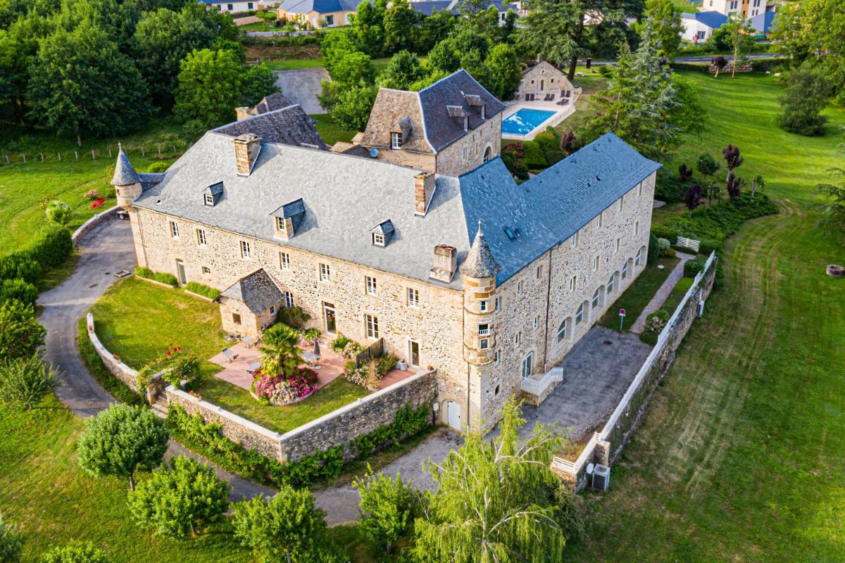 une vue aérienne d'une grande maison en pierre avec une cour dans l'établissement Château de la Falque, The Originals Relais, à Saint-Geniez-dʼOlt