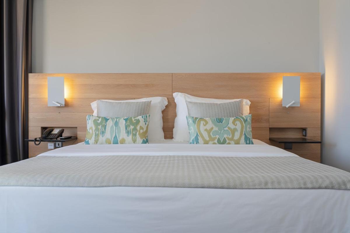 um quarto com uma cama grande com dois travesseiros em Madeira Panorâmico Hotel no Funchal