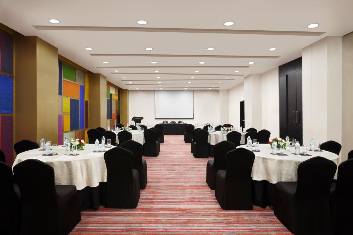 a conference room with tables and chairs and a screen at Crowne Plaza Pune City Centre by IHG in Pune +83 photos