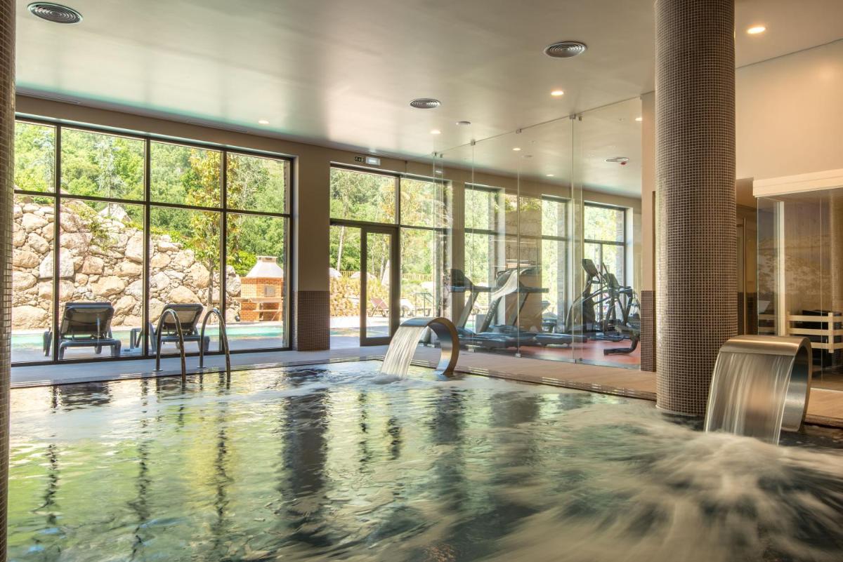uma grande piscina coberta com cascata em uma sala com janelas em Vila Galé Collection Serra da Estrela em Manteigas
