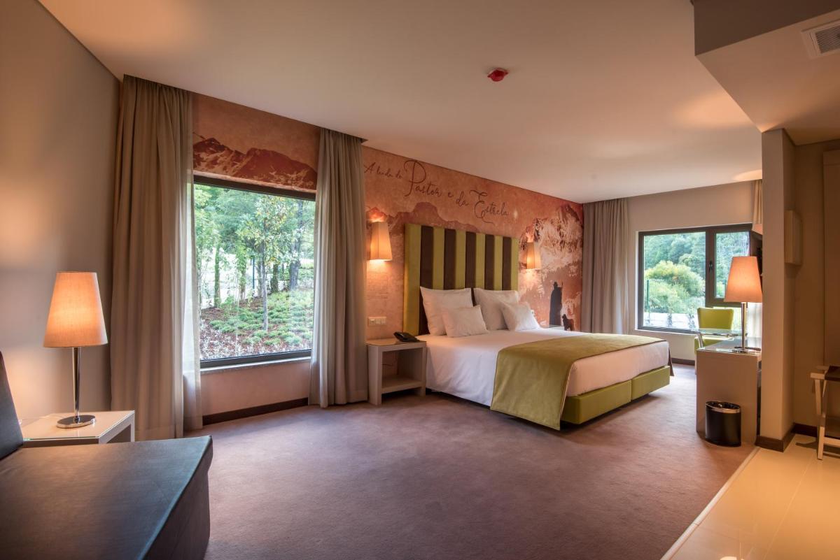 um quarto de hotel com uma cama e duas janelas em Vila Galé Collection Serra da Estrela em Manteigas