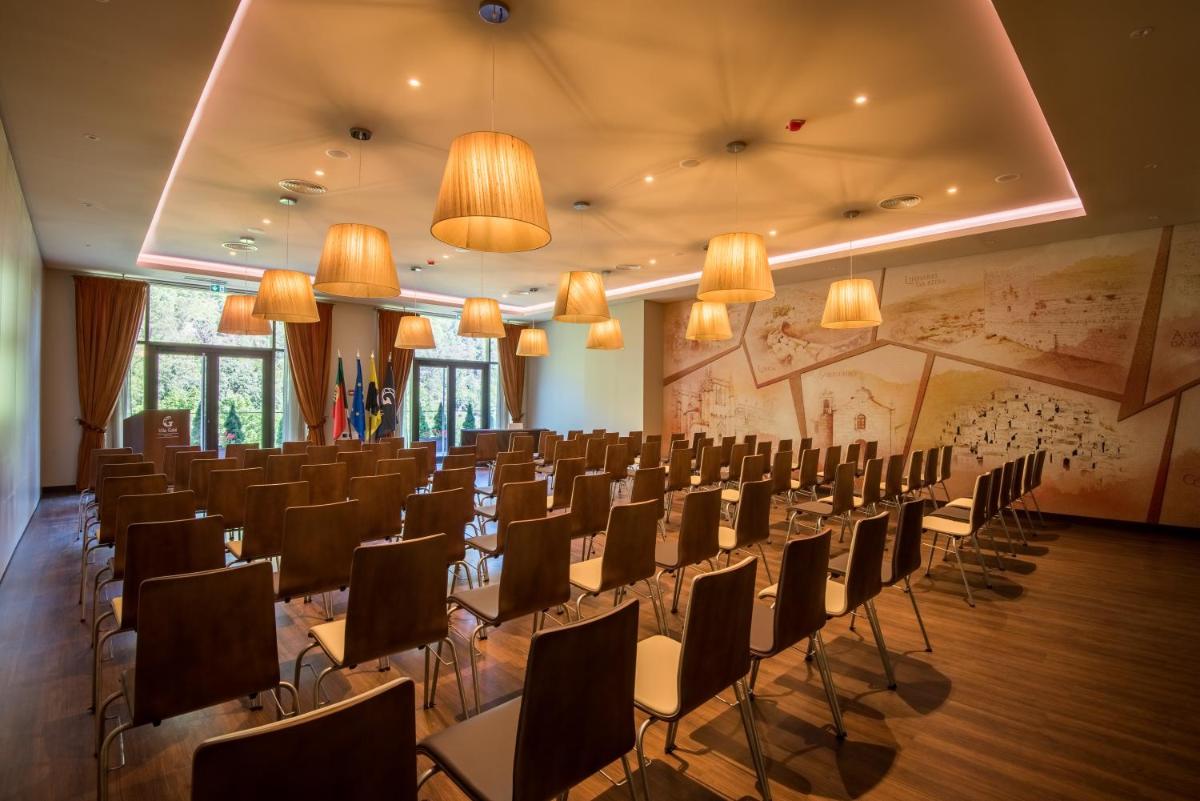 uma sala de conferências com cadeiras, mesas e lustres em Vila Galé Collection Serra da Estrela em Manteigas mais 85 fotografias