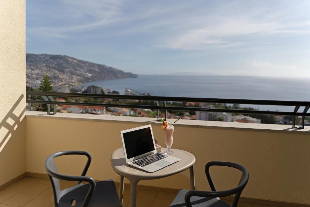 um computador portátil sentado numa mesa numa varanda em Madeira Panorâmico Hotel no Funchal mais 46 fotografias