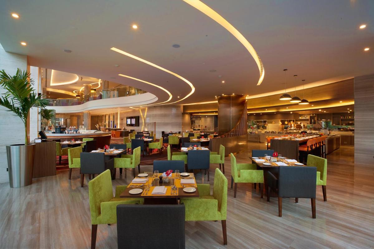 a dining room with tables and chairs and a restaurant at Novotel Ahmedabad in Ahmedabad