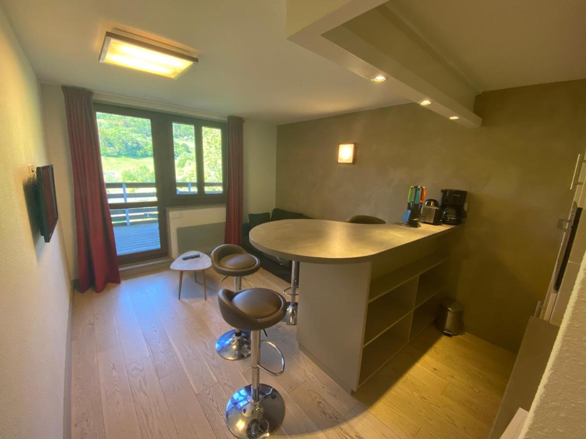 une pièce avec une cuisine équipée d'une table et de tabourets dans l'établissement Sancy Resort, à Chambon-sur-Lac