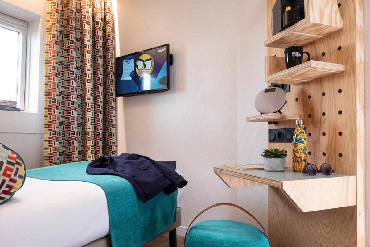 Cette chambre comprend un lit et une télévision murale. dans l'établissement Hotel Locomo - Gare de Lyon Bastille, à Paris