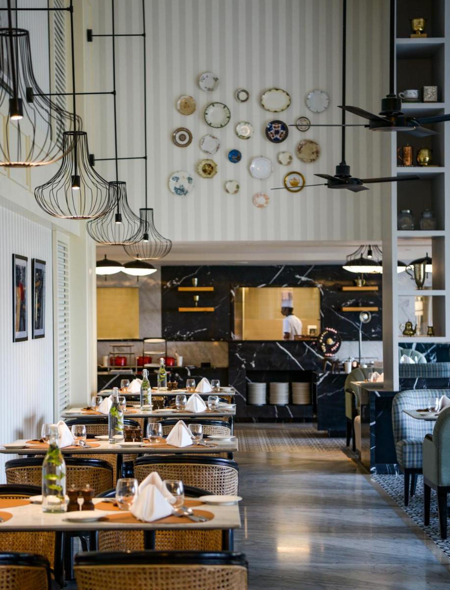 a restaurant with tables and chairs and plates on the wall at The Residency Towers Puducherry in Puducherry