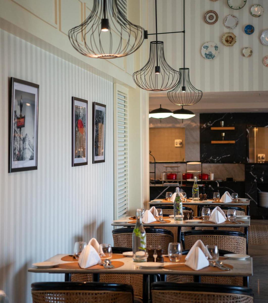 a dining room with tables and chairs and chandeliers at The Residency Towers Puducherry in Puducherry