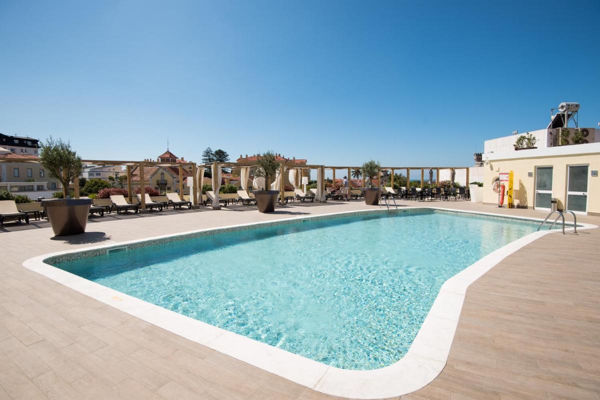 uma piscina em um hotel com mesas e cadeiras em Vila Galé Estoril em Estoril