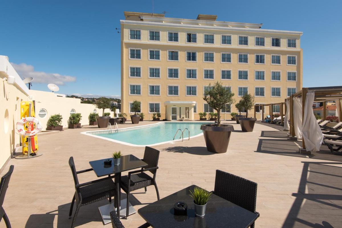 um hotel com piscina e cadeiras e um prédio em Vila Galé Estoril em Estoril