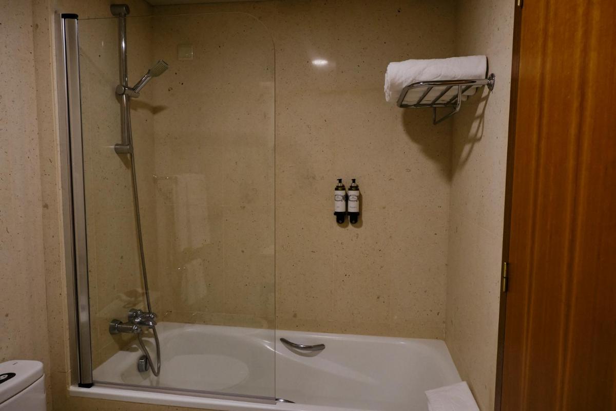 um banheiro com chuveiro, pia e banheira em Terceira Mar Hotel em Angra do Heroísmo
