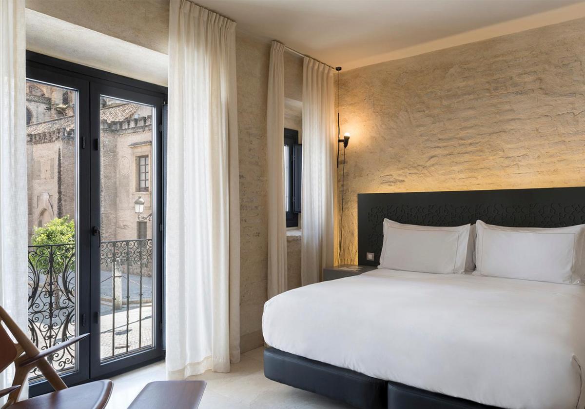 Un dormitorio con una cama grande y un balcón. en EME Catedral Mercer Hotel, en Sevilla