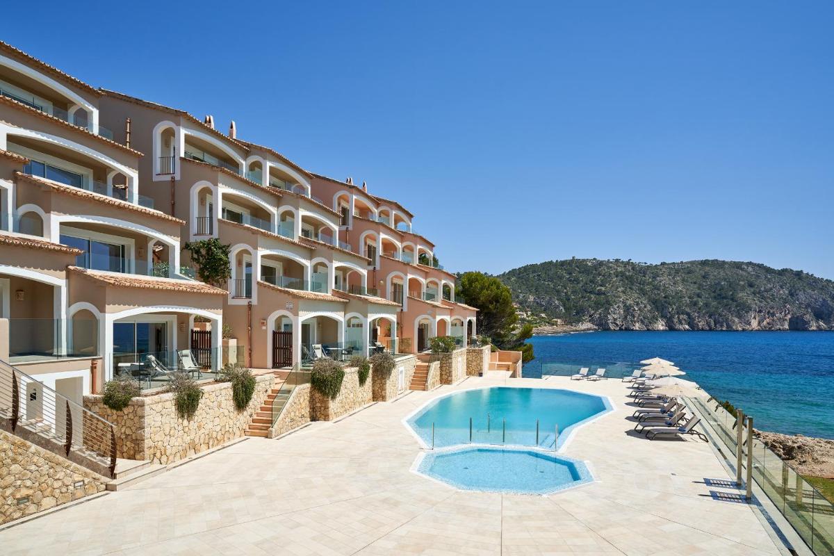 un hotel con piscina junto al agua en Bahia Suites Camp de Mar, en Camp de Mar