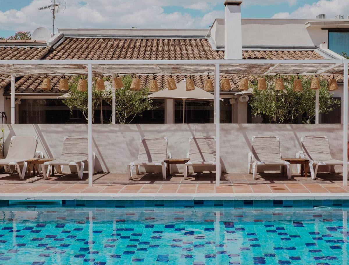 une piscine avec des chaises longues et une table à côté dans l'établissement Oustau Camarguen Hôtel & Spa, au Grau-du-Roi