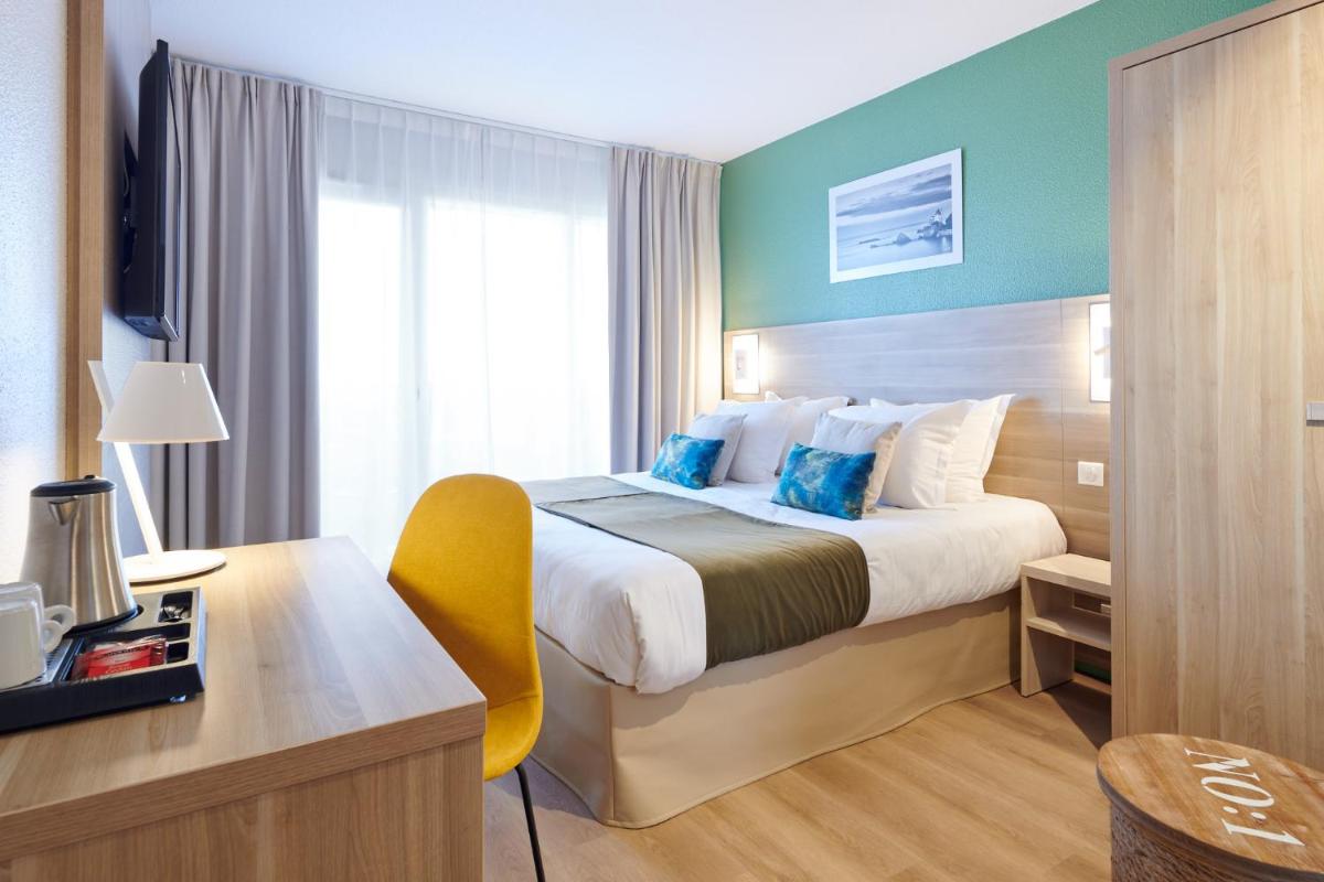 Cette chambre comprend un grand lit, un bureau et une chaise. dans l'établissement Les Terrasses d'Atlanthal, à Anglet