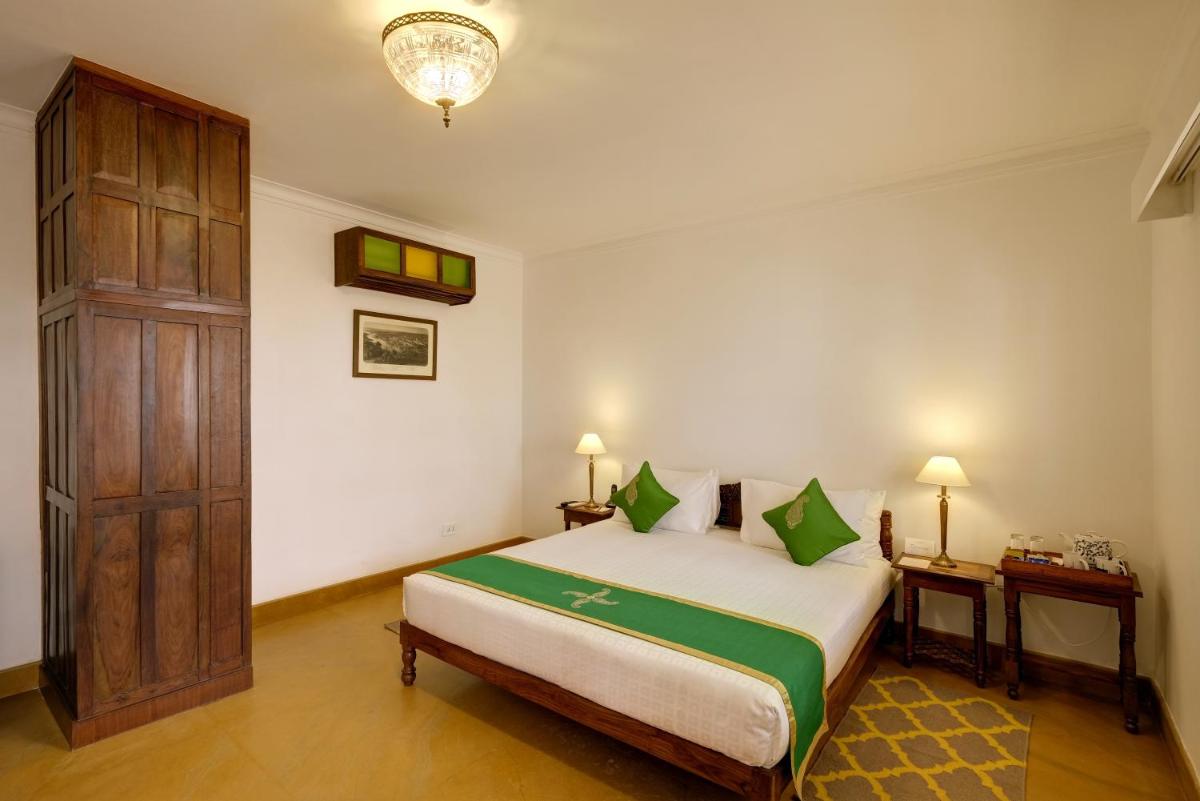 a bedroom with a large bed and a chandelier at Saraca Hotel Lucknow in Lucknow