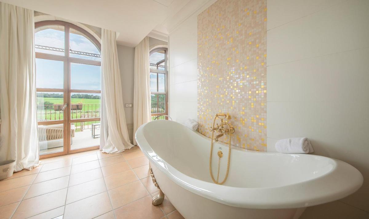 Una bañera blanca en un baño con ventana. en Casa Anamaria Hotel, en Ollers