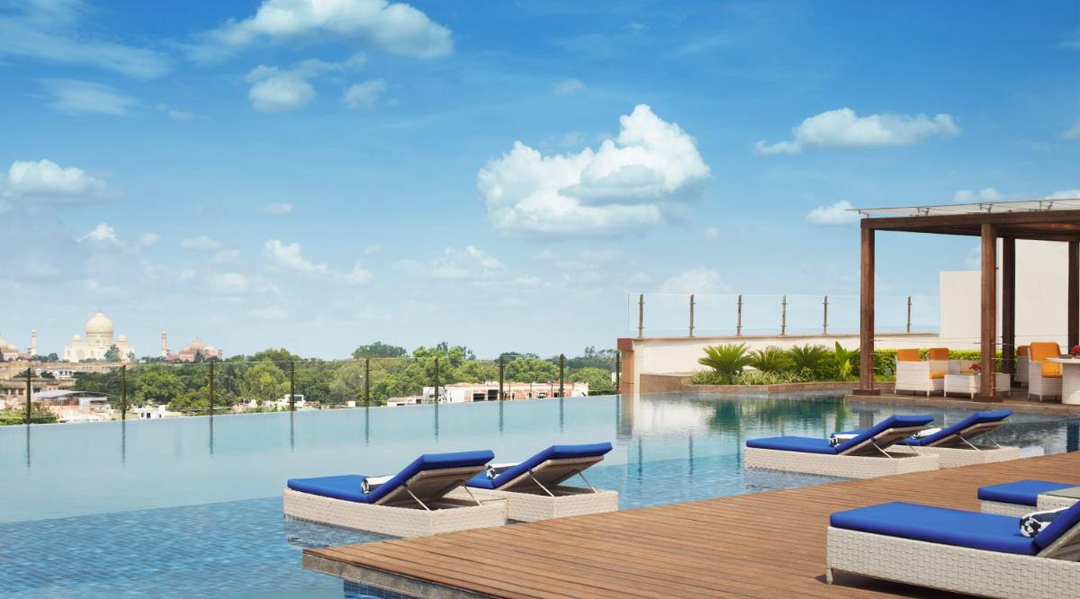 a group of lounge chairs on a swimming pool at Taj Agra in Agra