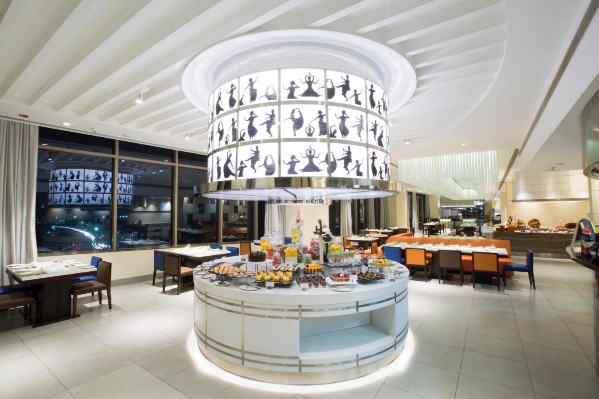 a restaurant with a large chandelier above a table at Holiday Inn Chennai OMR IT Expressway by IHG in Chennai