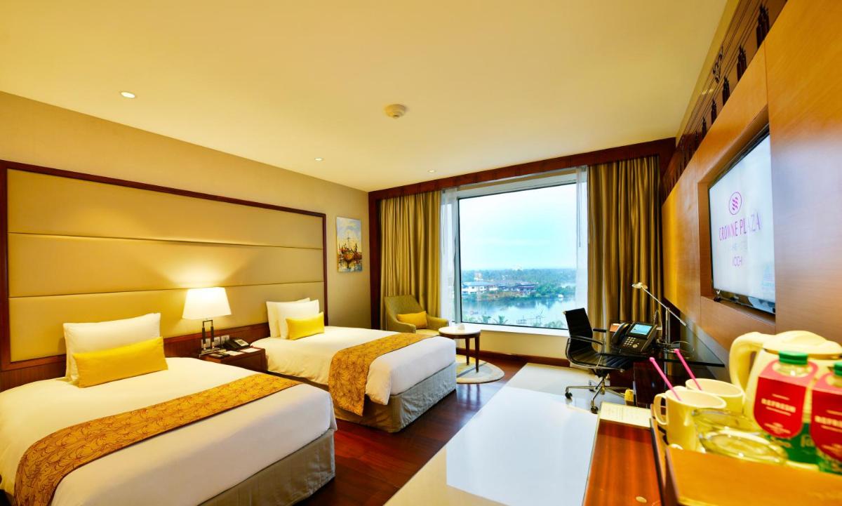 a hotel room with two beds and a large window at Crowne Plaza Kochi by IHG in Cochin