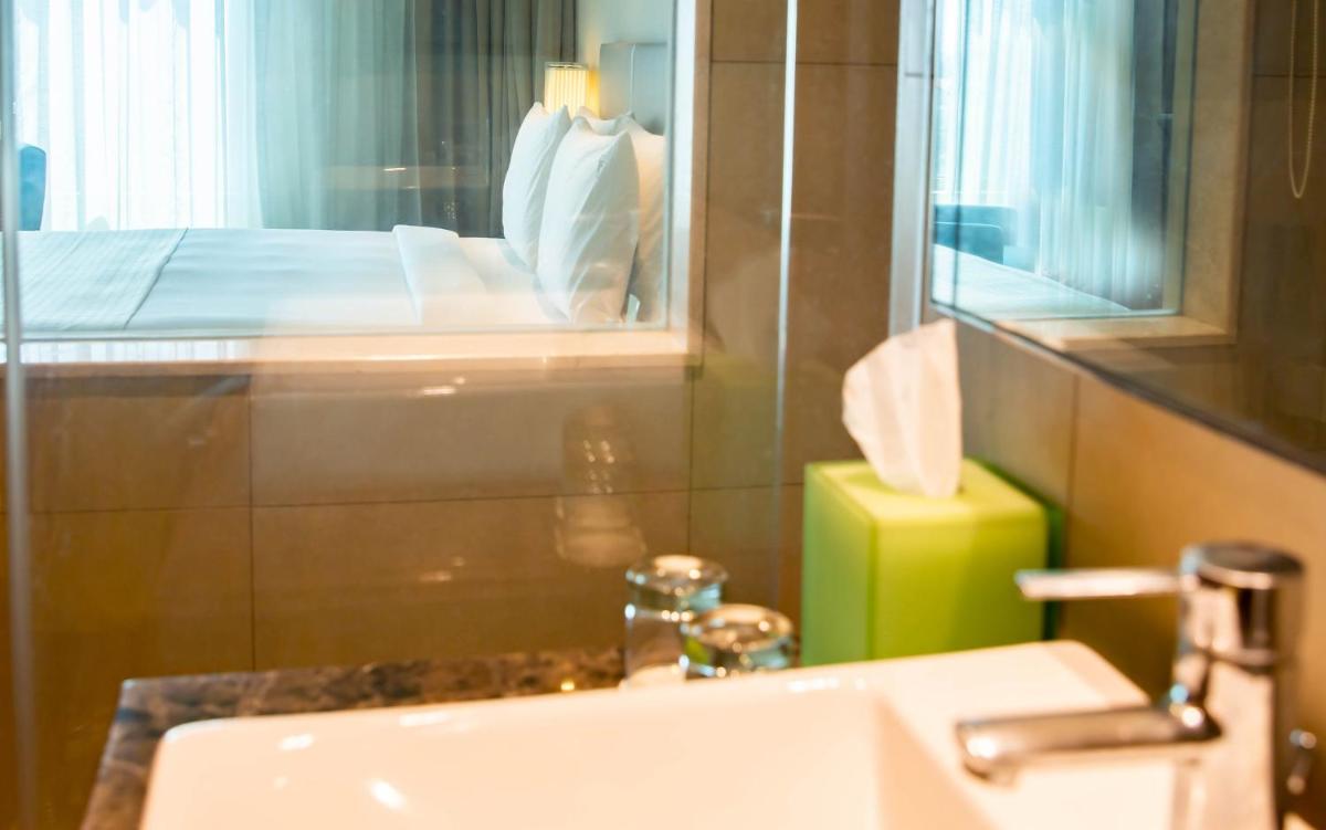 a bathroom with a sink and a bed in a room at Holiday Inn Chennai OMR IT Expressway by IHG in Chennai