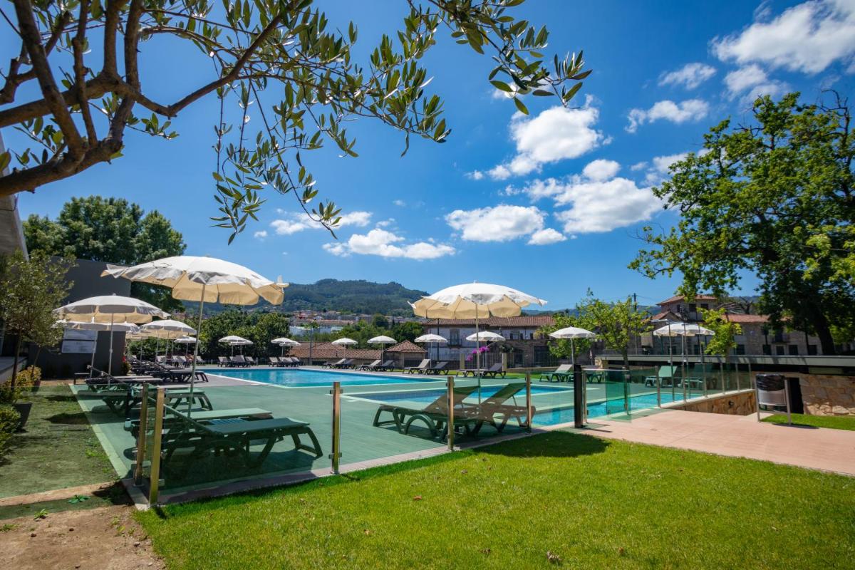 uma piscina com mesas e guarda-sóis em Luna Arcos Hotel Nature & Wellness em Arcos de Valdevez
