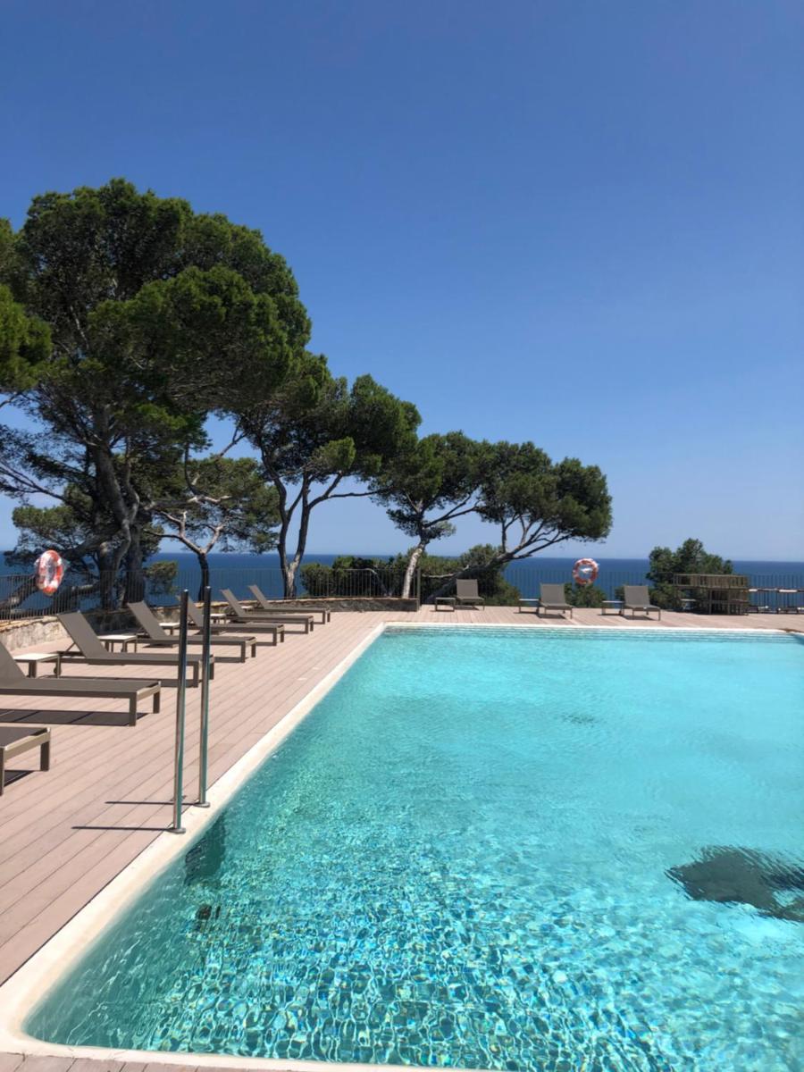 una piscina con sillas y árboles en el fondo en Parador de Aiguablava, en Begur