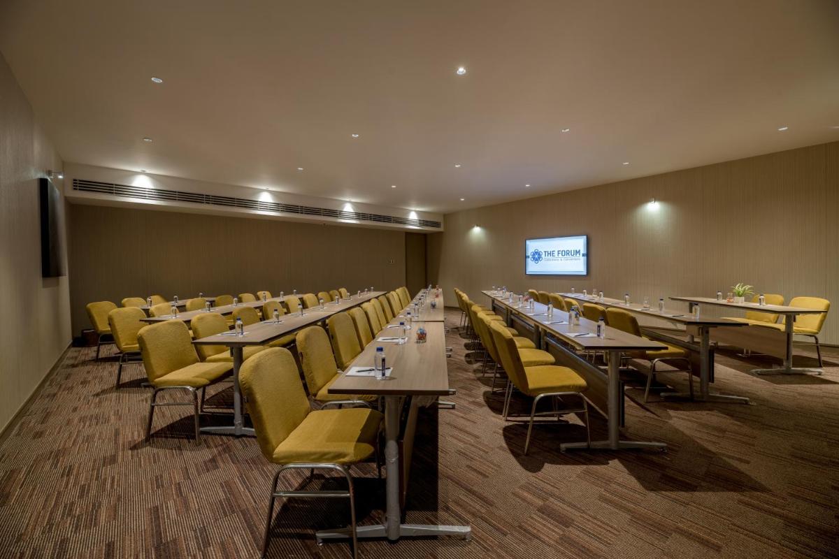 a conference room with tables and chairs and a screen at Wyndham Ahmedabad Shela in Ahmedabad
